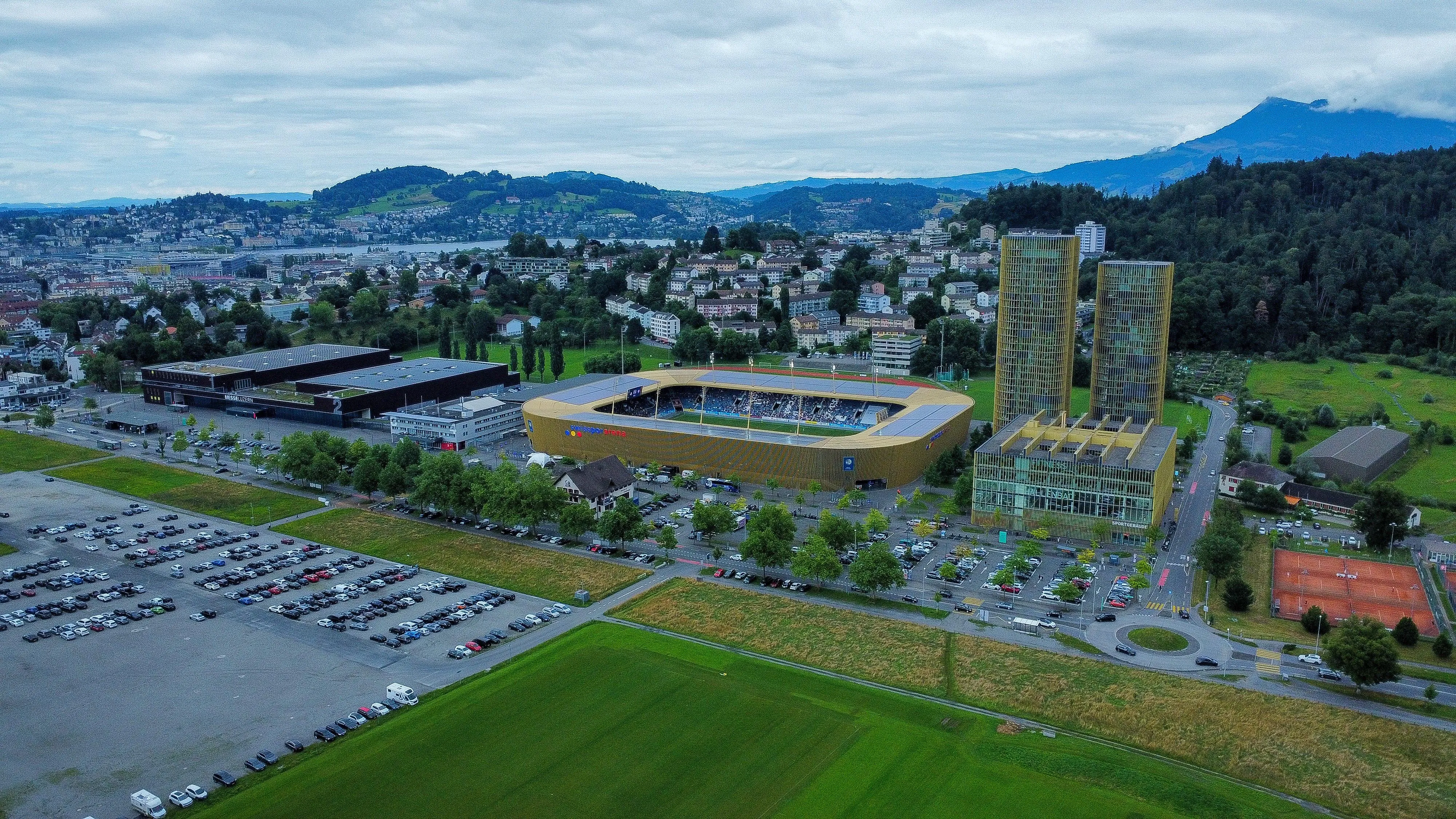 Stadion und Hochhäuser mit Bergpanorama aus der Vogelperspektive