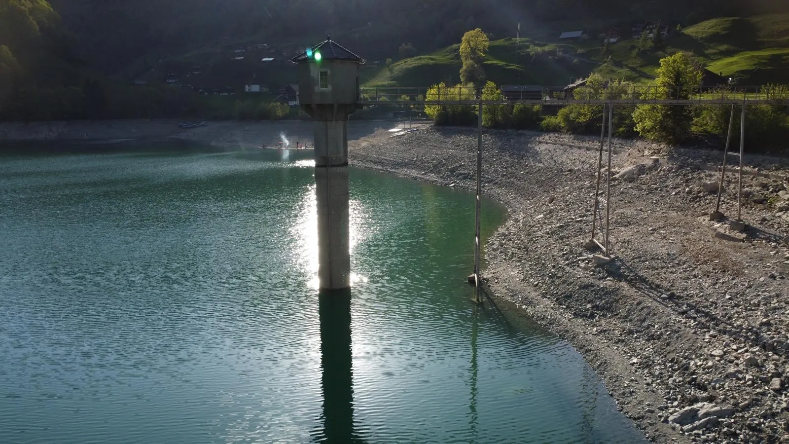 Turm in einem türkisfarbenen Bergsee im Gegenlicht